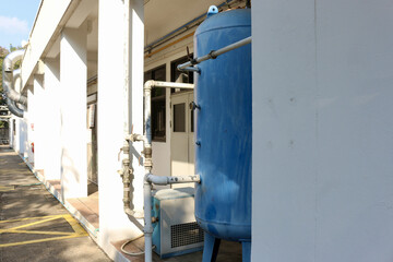 Industrial water tank beside building with pipes and machinery