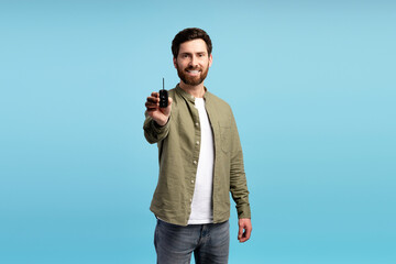 Young overjoyed smiling cheerful man wearing casual t shirt, holding car keys in studio