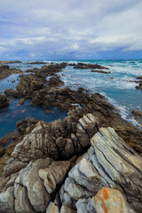 Beautiful rocky shoreline in South Africa during a cloudy afternoon with blue water