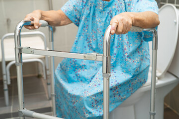 Asian elderly woman patient use walker and toilet bathroom handle security in nursing hospital,...