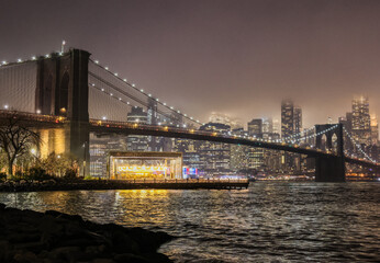 Fototapeta premium Manhattan skyline and Brooklyn Bridge on a foggy December night