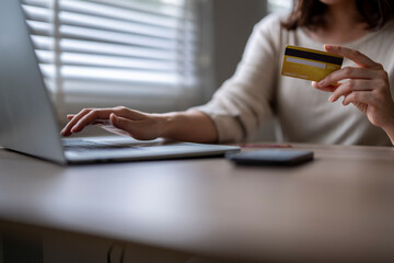 A woman is using a laptop to pay for something with a credit card