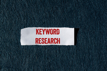 Keyword research message written on ripped torn paper piece with gray background. Conceptual...