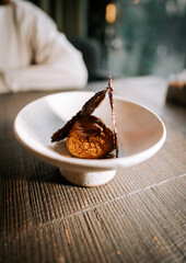 Unique dessert presentation with chocolate and biscuit elements served on a fine dish in a modern restaurant setting
