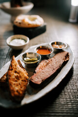 Sliced brisket served with sides of pickles and sauces in a casual dining setting