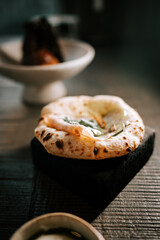 Freshly baked flatbread with herbs served on a wooden table in a cozy dining setting