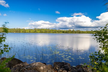 Ruhiger See mit blauem Himmel und weißen Wolken