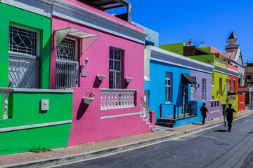 Colorful houses lining a street in Cape Town with vibrant murals under a clear blue sky