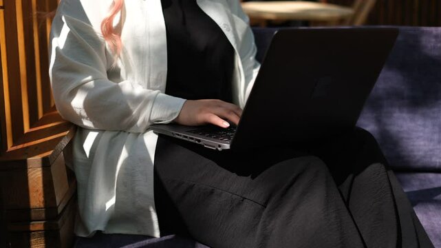 young fat woman working at a computer on the terrace in a cafe on a summer day