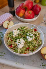 Healthy raw fruit vegetable salad with apples and zucchini topped with protein rich cottage cheese