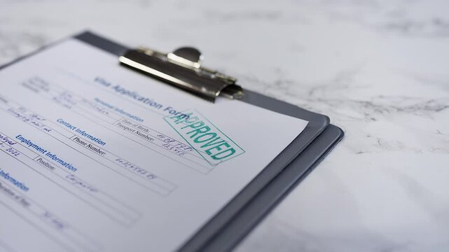 Visa application form gets approved as a hand stamps a seal on the document