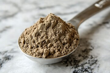 Brown powder in a metal spoon on marble.
