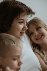 A loving mother with her son and daughter enjoys the magical atmosphere of Christmas and New Year. The family shares joyful moments, playing together, laughing, and creating warm holiday memories