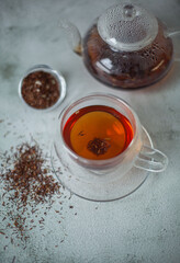 A tea cup on a table with a teapot and scattered tea leaves