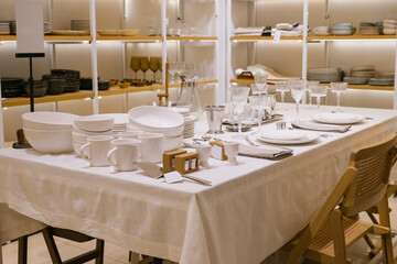 Elegant dining table setting with white dinnerware and crystal glasses in modern store display