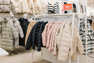 Display of various puffer jackets in clothing store with price tag. Shopping Cart Day