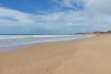 Fototapeta premium Deserted sandy beach with waves and cloudy sky. Tranquil seascape photography.