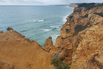 Dramatic coastal cliffs overlooking ocean waves under cloudy skies