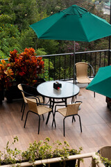 La terraza con sombrillas verde y sillas de metal negro, es un lugar tranquilo en un entorno de naturaleza
