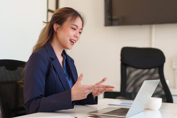 Young Asian businesswoman having a virtual meeting, discussing work while sitting in a professional office setting