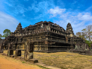 The beautiful corner of Baphuon temple with good blue sky and dry grass floor in Angkor wat and Angkor Thom at Siem Reap, Cambodia.