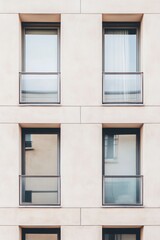 Modern apartment building facade showcasing sleek lines and multiple windows with minimalist balconies in an urban setting during daylight