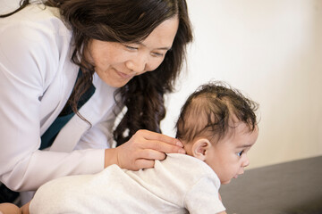 Doctor checking baby's neck in office