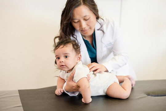 Baby laying on exam table while doctor evaluates him