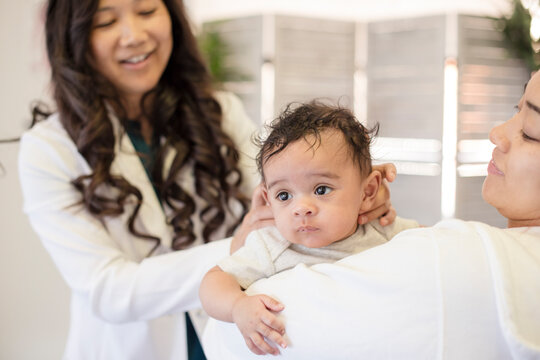 Doctor evaluating baby while mom holding him