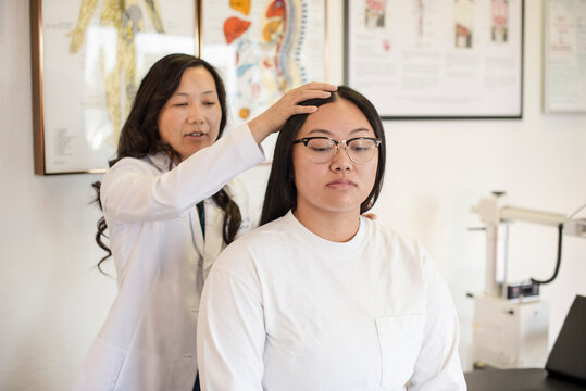 Doctor evaluating patient's neck at hospital