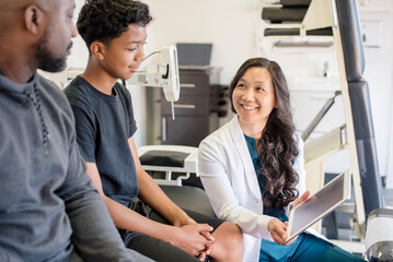 Woman doctor showing patient and father information on tablet
