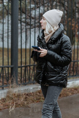 Fototapeta premium A beautiful young woman walks through a snowy city on a winter day, joyfully chatting on her phone. She smiles and laughs, radiating warmth and happiness. The clip captures a cozy lifestyle vibe