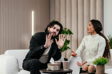 Angry husband and african american wife, biracial couple fighting discussing family problems during session with therapist in office. Relationship and psychology concept