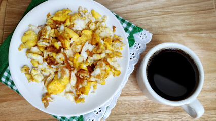 Healthy breakfast with scrambled eggs and coffee cup on the wooden table in homely atmosphere.