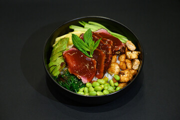 An Asian bowl with a vibrant mix of vegetables, meat or fish, served on a bed of rice in a sleek black bowl. The dish showcases a colorful and nutritious combination, perfect for a modern restaurant 