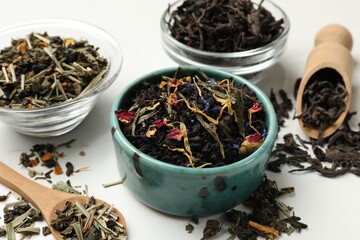 Different dry tea leaves on white table, closeup