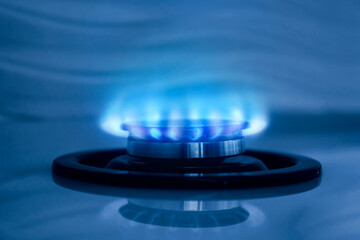 Gas burner with blue flame on stove, closeup