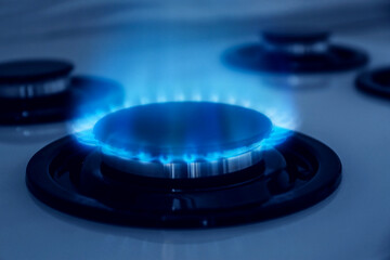 Gas burner with blue flame on stove, closeup