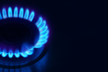 Gas burner with blue flame on stove, closeup. Space for text
