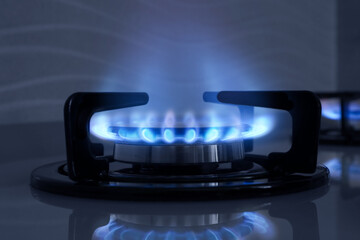 Gas burner with blue flame on stove, closeup
