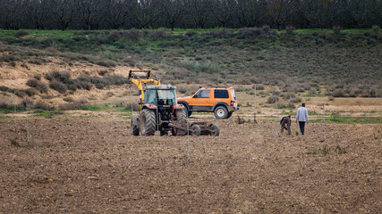 two people working in the field with their tractor and 4x4 vehicle