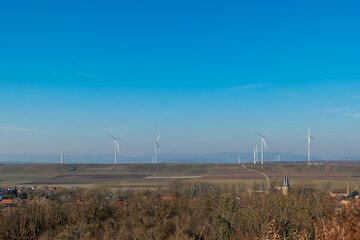 A clear view of wind turbines on rolling hills in a rural landscape under a vibrant blue sky