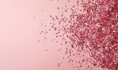 Shimmering pink glitter scattered on pastel pink background creates sparkling and festive atmosphere. glitter reflective quality adds touch of elegance and celebration