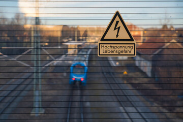 Warnung vor Hochspannungsgefahr auf der Brücke über die Eisenbahn.