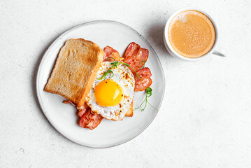 Fried egg and bacon breakfast sandwich and coffee