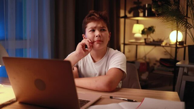 Portrait of cute little boy studying thinks questioningly about difficult choice choose imagine plan in mind has doubts late at night at home workplace	