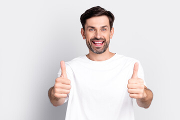 Fototapeta premium Smiling Young Man Showing Thumbs-Up Gesture in a White T-Shirt Against a Light Grey Background