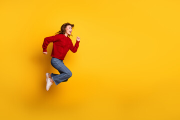 Obraz premium Energetic young woman in casual attire jumping joyfully with a yellow background