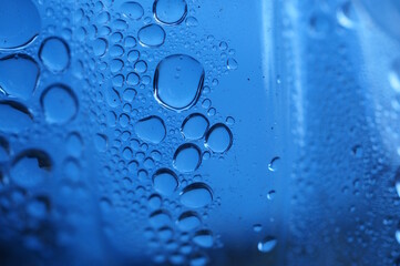 Abstract blue background. Drops of water on a plastic bottle.