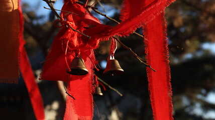 Rustic Bells with Red Cloth Tapes Hanging from Tree Branches